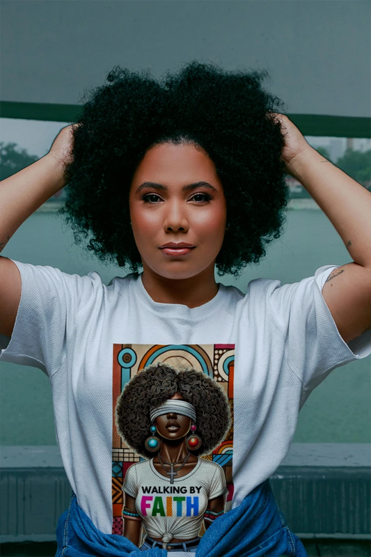Woman wearing a white t-shirt with a graphic of another woman with an afro and 'Walking by Faith' text.
